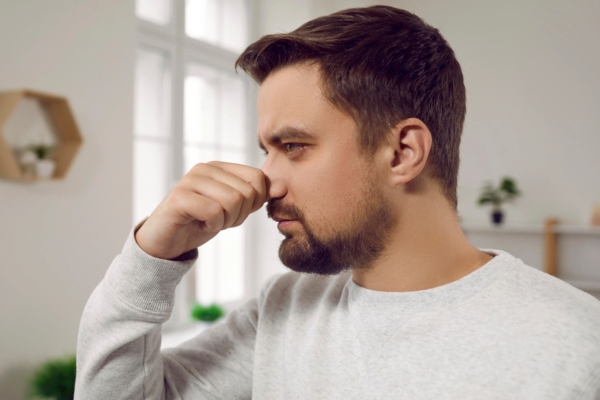 man covering his nose due to unusual smell from furnace