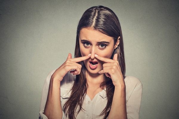 image of woman covering nose from bad furnace odor