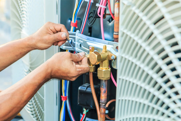 image of an HVAC contractor performing annual air conditioner maintenance