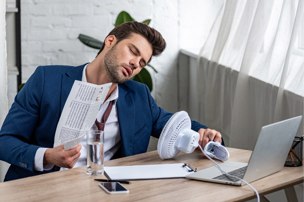 man sitting in front of fan due to high humidity