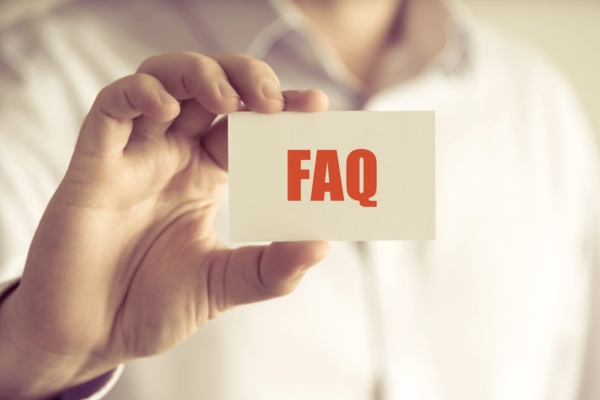 cropped view of a man's hand holding a card that says FAQ depicting questions about Signs of Leaky Air Ducts