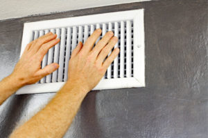 image of a homeowner placing hands in front of hvac air vent to check for airflow