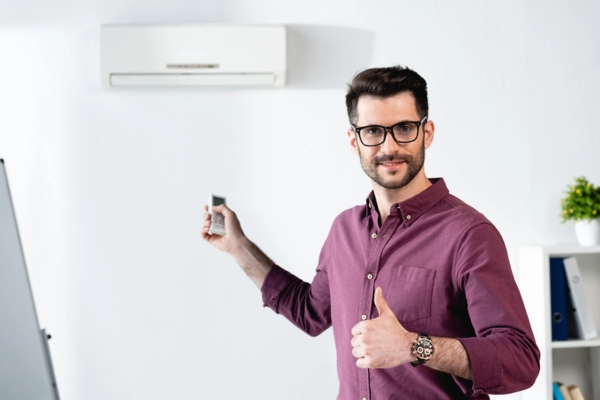 homeowner doing a thumbs up gesture while turning on air conditioner