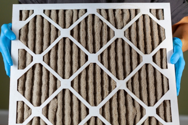 homeowner wearing blue gloves removing dirty HVAC filter