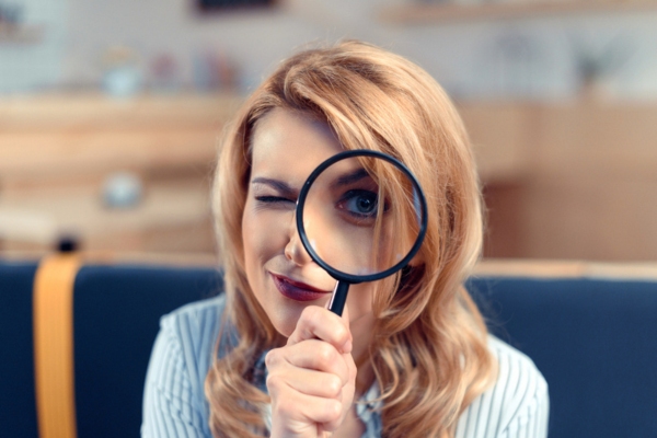 woman with magnifying glass with eye depicting early detection of air conditioner issues