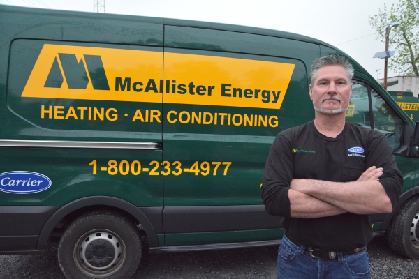 McAllister Energy HVAC technician standing beside a service van