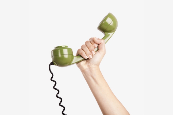 hand holding home phone with cord depicting calling HVAC Company
