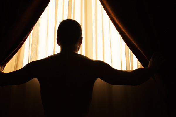 homeowner using blackout curtains to prevent heat from entering room