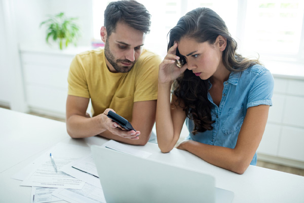 Worried couple calculating their energy bills with laptop in the kitchen