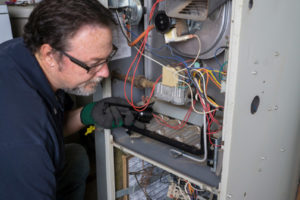 image of an hvac technician repairing a furnace that is leaking