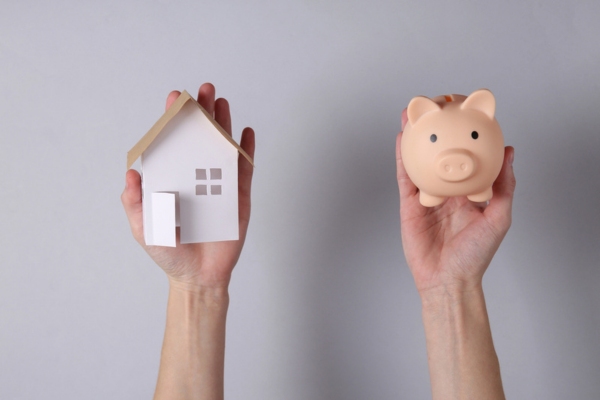 man's hands holding miniature house and piggy bank depicting Cost Savings for Homeowners