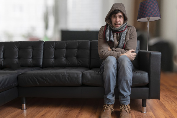 image of a homeowner feeling chilly due to furnace not turning on with thermostat