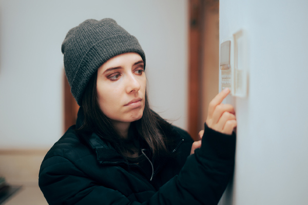 image of homeowner adjusting thermostat depicting heat pump not reaching temperature in winter