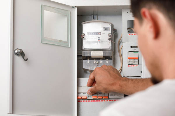 image of a homeowner at electrical panal checking heat pump circuit