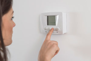 image of homeowner adjusting heat pump thermostat since heat pump compressor not turning on
