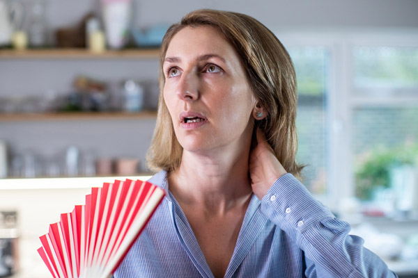 image of a homeowner using a fan to keep cool due to frozen heat pump