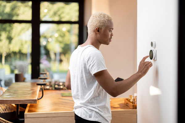 image of homeowner adjusting programmable thermostat for air conditioner