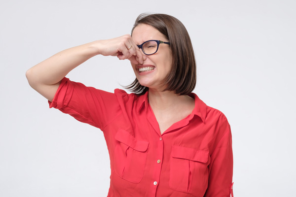 woman plugging nose due to smelly odors at home