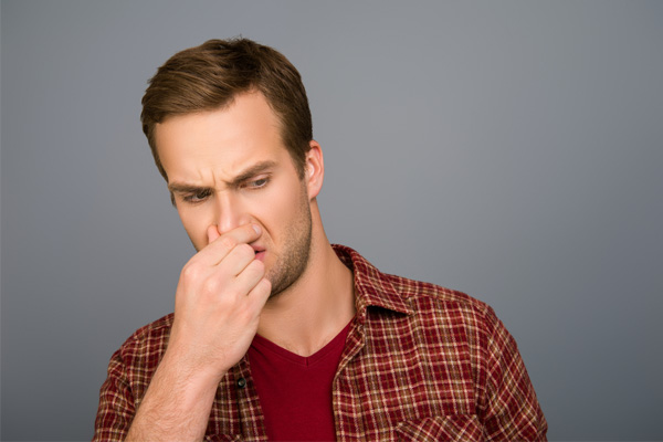 image of a homeowner plugging nose due to furnace odor and overheating