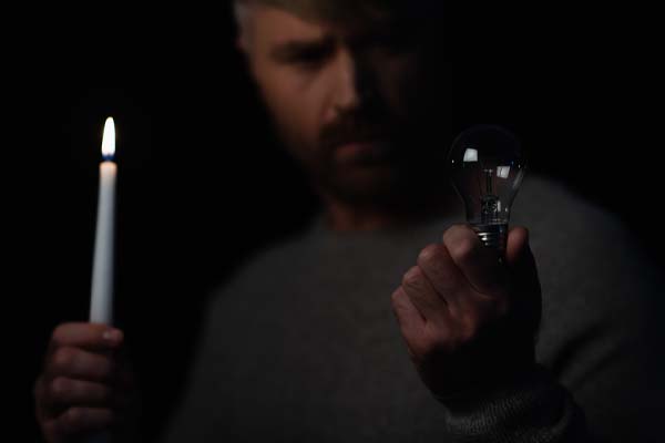 image of a homeowner during a power outage who requires a new backup generator