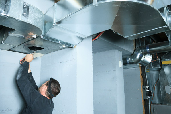 hvac technician repairing leaky ductwork