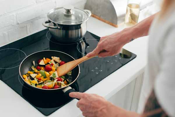 image of a homeowner cooking and using mechanical ventilation to prevent odors