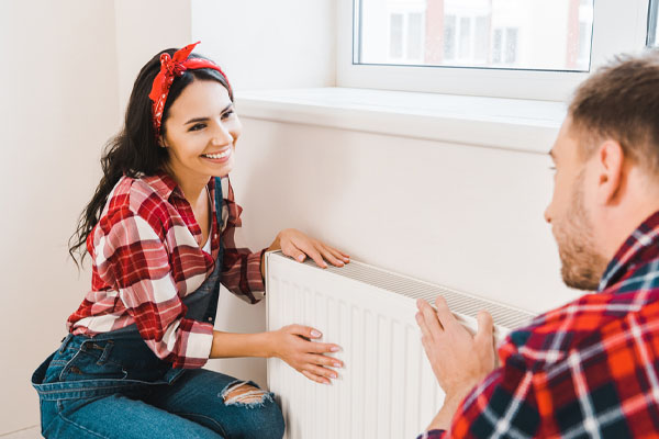 image of a homeowner talking to hvac contractor near radiator of a boiler