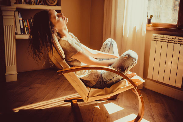 woman relaxing in front of radiator of a boiler system at home