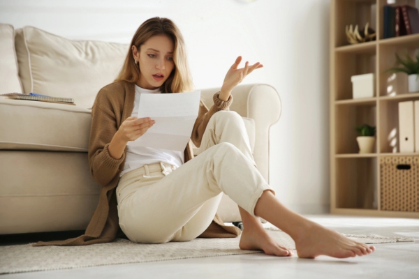 shocked woman looking at electricity bill depicting signs of inefficient air conditioner