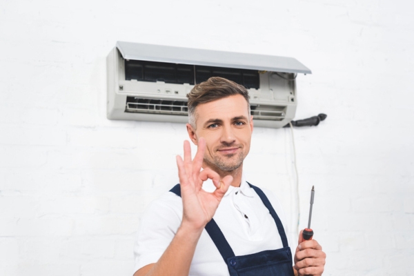 HVAC technician doing an okay sign after installing ductless system