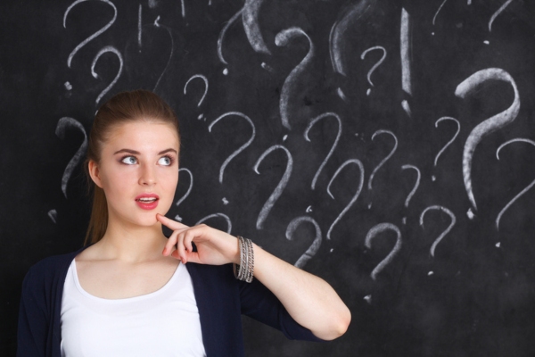 image of a woman wondering beside question marks written on a chalkboard depicting why AC freezes & what to do