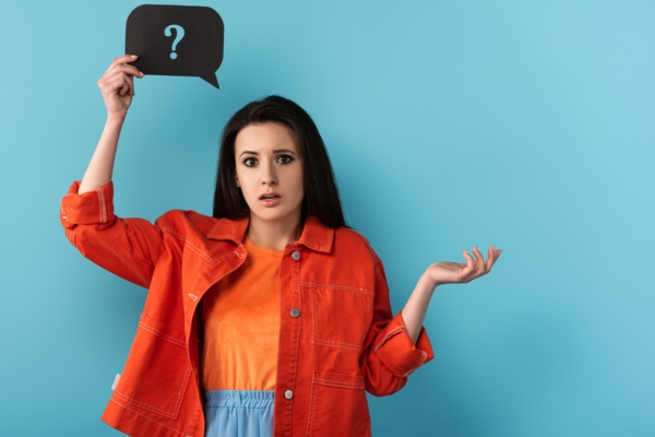 woman holding a speech bubble cutout with question mark depicting difference between ductless heat pump and ductless AC