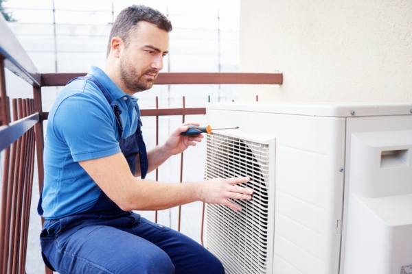 HVAC technician attending to an air conditioner outdoor unit