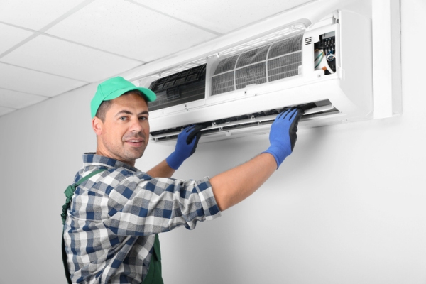 HVAC technician inspecting indoor ductless air conditioner