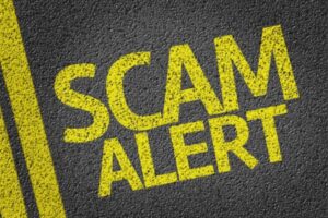 scam alert spray painted on concrete road depicting air conditioning scams