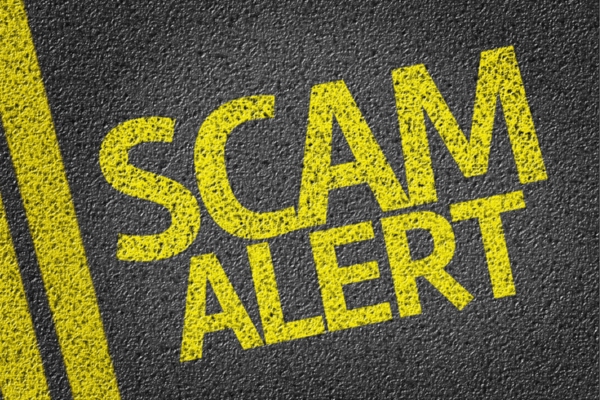 scam alert spray painted on concrete road depicting air conditioning scams