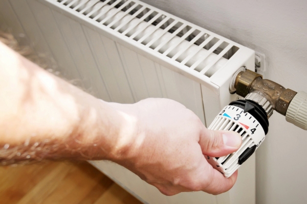 cropped view of a man's hand adjusting heating radiator
