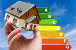 hand holding a miniature house up with an energy efficiency chart in the background depicting heating oil efficiency