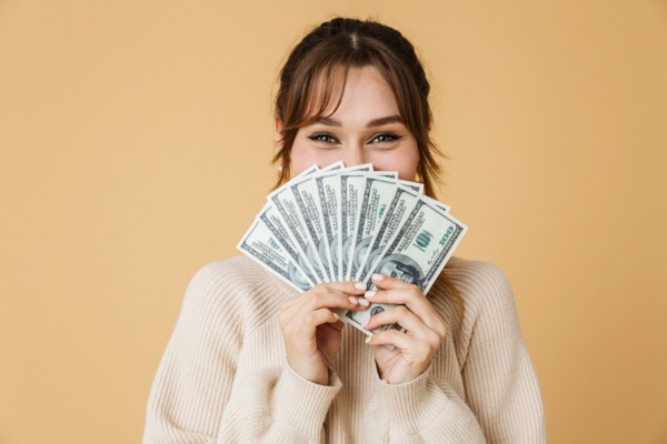 woman holding dollar bills covering the bottom half of her face depicting affordability of heating oil