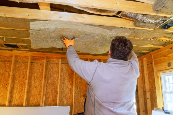 worker puts insulation in the ceiling of the house
