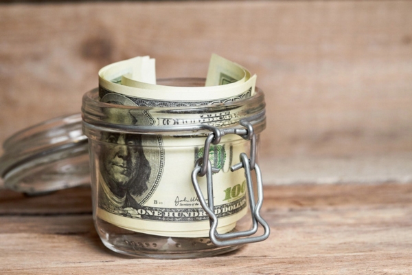dollar bills inside a glass jar depicting Reduced Heating Expenses