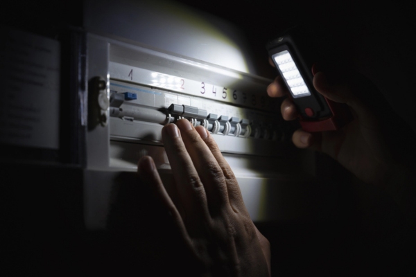 homeowner investigating a home fuse box during a power outage