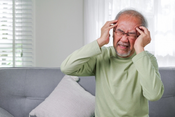 senior man with hands on temples while nursing a headache depicting Carbon Monoxide Accumulation Concerns