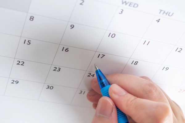 woman's hand about to write on a pen depicting Scheduling and Seasonal Readiness
