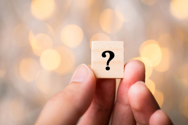 hand holding a wooden chip with a question mark depicting Air Conditioner Repair vs Replacement