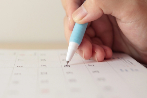Hand with pen writing on calendar depicting Ideal Schedule for Replacing Your HVAC Air Filter