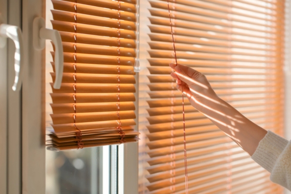 woman closing blinds at home to keep home cool