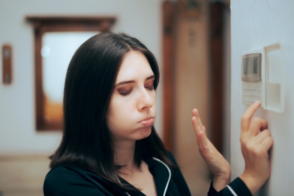 woman feeling hot while controlling home thermostat depicting AC won't turn on
