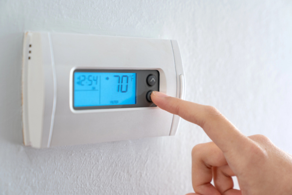 homeowner adjusting programmable thermostat