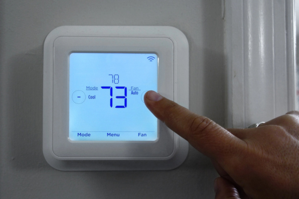 homeowner adjusting smart wifi thermostat